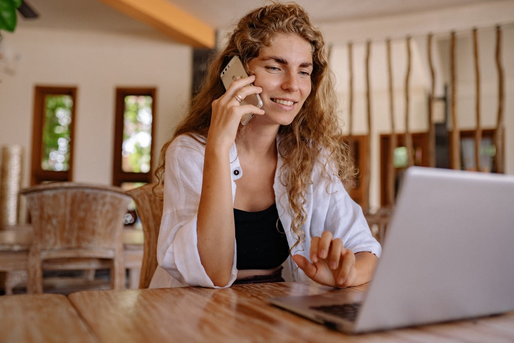 A lady working on a laptop and making a call