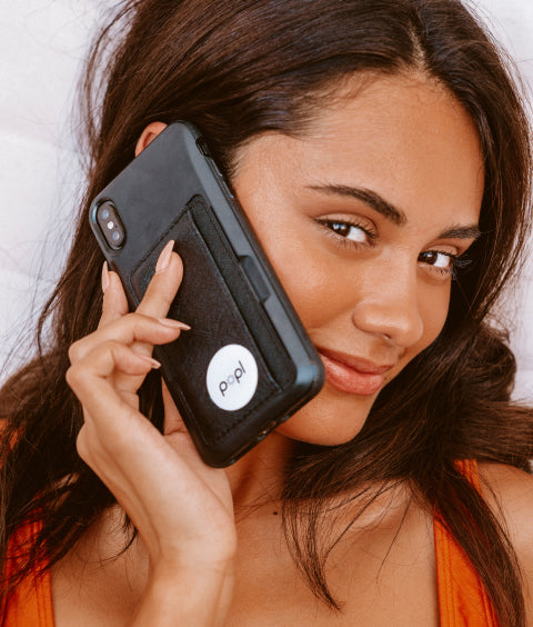 Woman holding a cellphone with Popl on its back